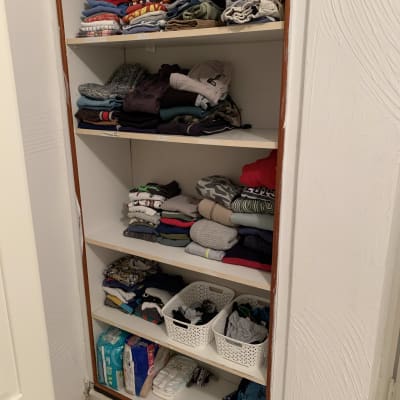 ארון בגדים מסודר עם בגדים מקופלים וסלים לבנים