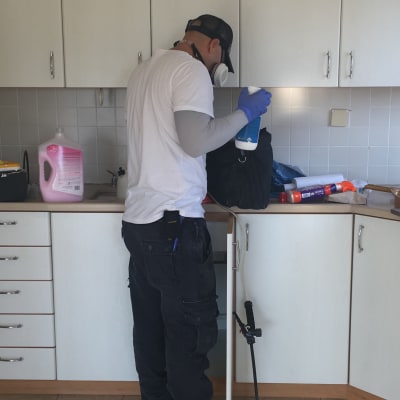 מדביר עם מסכה וכפפות מחזיק חומר הדברה במטבח