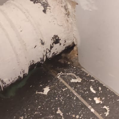 צינור לבן עם קילופים וחור בקיר