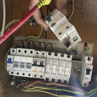 לוח חשמל עם מפסקים וחוטים, יד מחזיקה מפסק שרוף