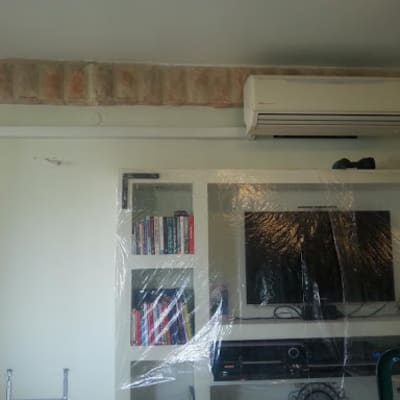 מזגן מותקן על קיר מעל טלוויזיה עטופה בניילון