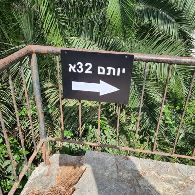שלט עם חץ על מעקה חלוד