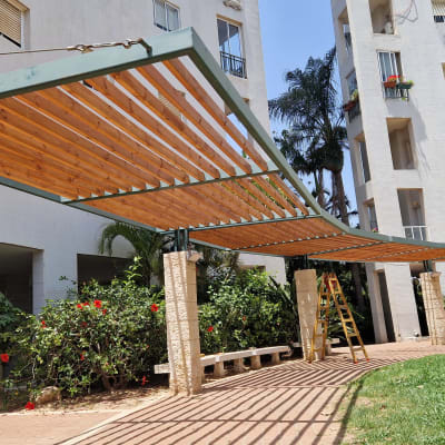 פרגולה מעץ ומתכת בגינה ציבורית עם סולם