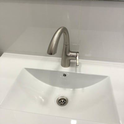 ברז נירוסטה מותקן על כיור לבן בחדר אמבטיה