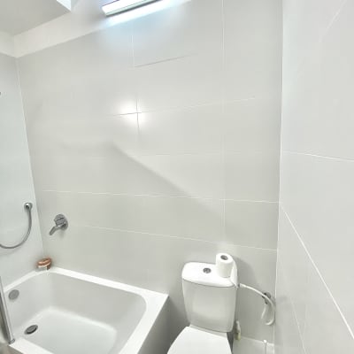 חדר אמבטיה עם אריחים לבנים, אמבטיה ושירותים