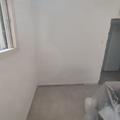 קיר צבוע בלבן עם חלון פתוח וציוד מכוסה בניילון