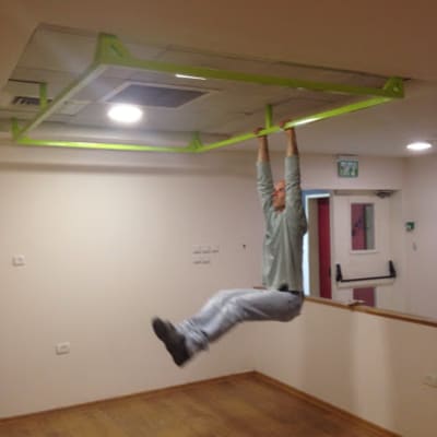 אדם תלוי על מסגרת מתכת ירוקה בתקרה