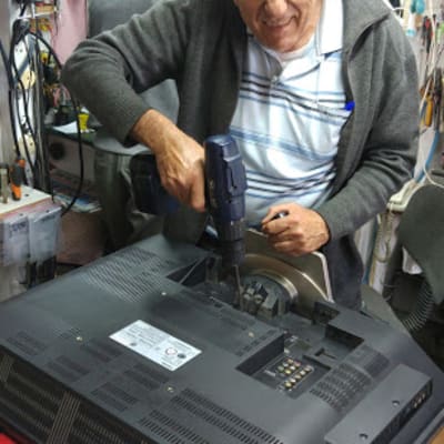 אדם מתקן טלוויזיה עם מברגה בחנות אלקטרוניקה