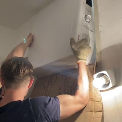 אדם מזיז מכונת כביסה עם קרטון להגנה