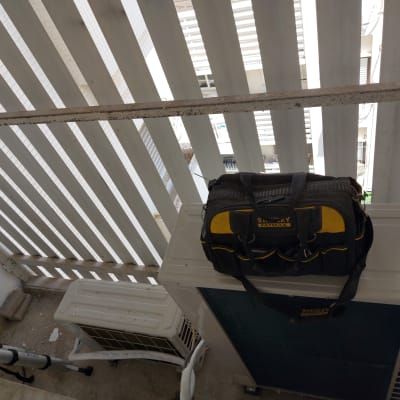 תיק כלים על מזגן ליד סולם ומעקה