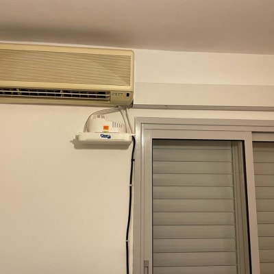 מזגן מותקן על קיר מעל חלון עם תריסים