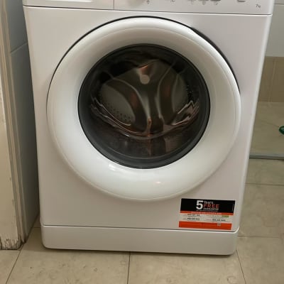 מכונת כביסה לבנה עם לוח בקרה וכפתורים