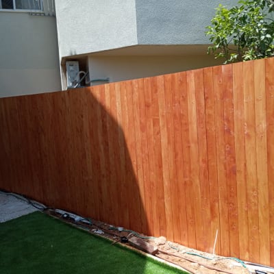 גדר עץ ליד דשא מלאכותי וצינורות השקיה