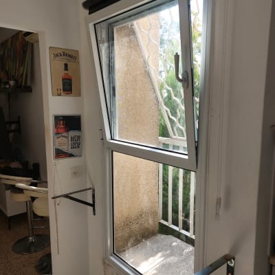 חלון אלומיניום פתוח עם מסגרת לבנה