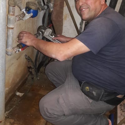 אדם עובד על צינורות עם מפתח צינורות