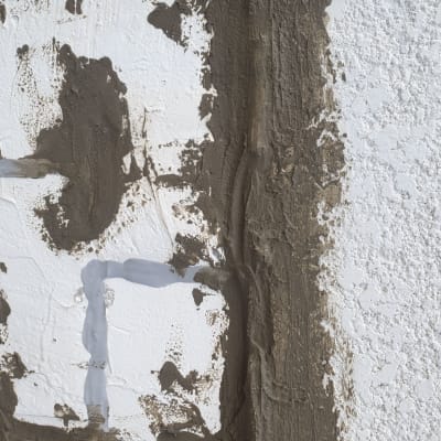 מריחת חומר איטום על קיר לבן