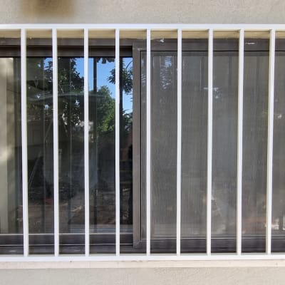 חלון עם סורגים לבנים על קיר בטון