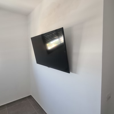 טלוויזיה מותקנת על קיר לבן בחדר