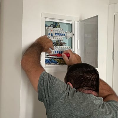 חשמלאי עובד על לוח חשמל עם מברג אדום