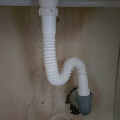 צינור ניקוז לבן מתחת לכיור עם חיבור אפור