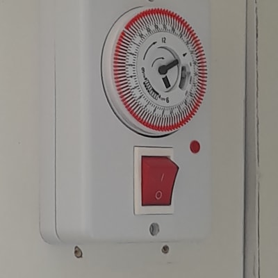 טיימר חשמלי עם מתג אדום על קיר