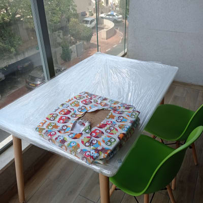 שולחן עטוף בניילון עם כיסאות ירוקים למעבר דירה