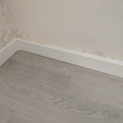 רצפת פרקט אפורה עם פאנל לבן ליד קיר מתקלף