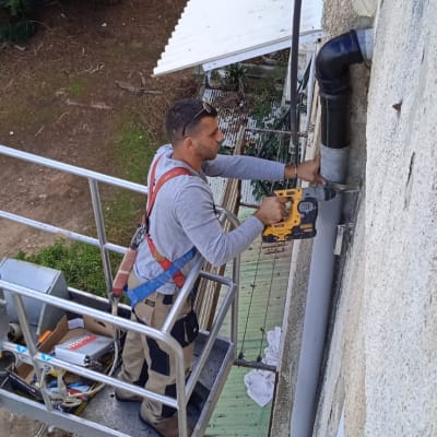 אדם על פיגום מתקין צינור על גג מתכת