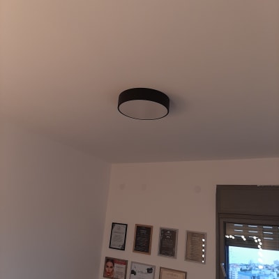 Ceiling light fixture in a room with certificates on the wall.