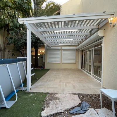 בריכת שחייה חיצונית ליד פרגולה לבנה בגינה