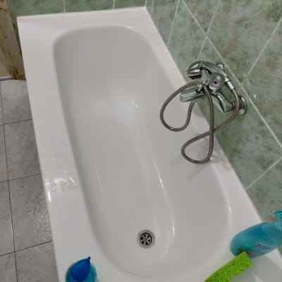 אמבטיה לבנה עם ברז מתכת ומוצרי ניקוי