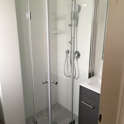 מקלחון זכוכית עם ראש מקלחת ומדף מתכת