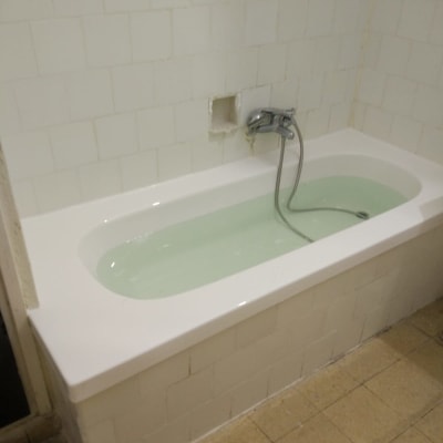 אמבטיה עם חיפוי אריחים לבנים וברז מותקן