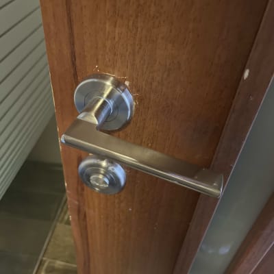 ידית דלת מתכתית על דלת עץ