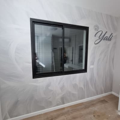 קיר עם טפט נוצות לבנות וחלון שחור