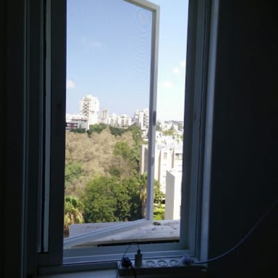 חלון אלומיניום פתוח עם נוף עירוני ברקע