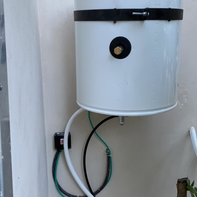 דוד שמש לבן עם צינורות מחוברים לקיר