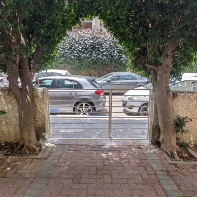 שער מתכת בין שני עצים עם מכוניות ברקע