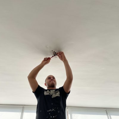 חשמלאי עובד על תקרה עם כלי עבודה