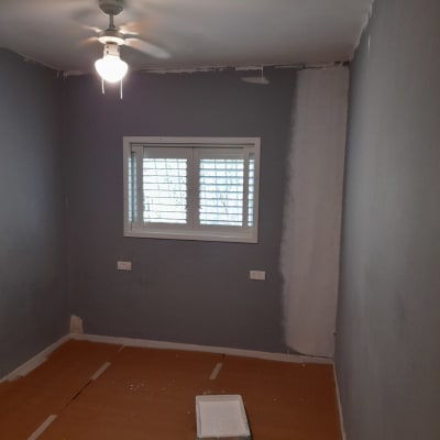 חדר צבוע חלקית עם ציוד צביעה על הרצפה