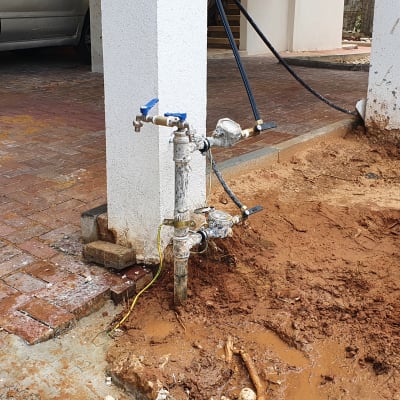 ברזי מים וצינורות ליד עמוד בטון