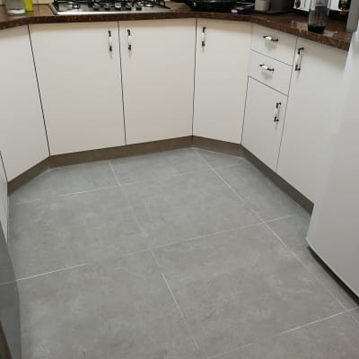 מטבח עם ארונות לבנים ורצפת אריחים אפורה