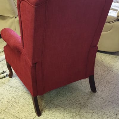 כורסה מרופדת באדום עם רגלי עץ כהות