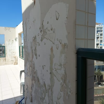 קיר עם צבע מתקלף ומטאטא על הרצפה