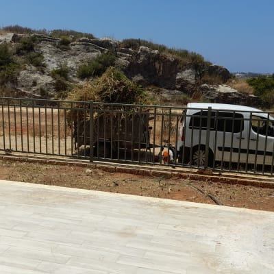 אדם עם שקי גזם ליד רכב לבן בגינה