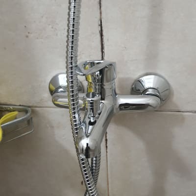 ברז כרום עם צינור מקלחת על קיר אריחים