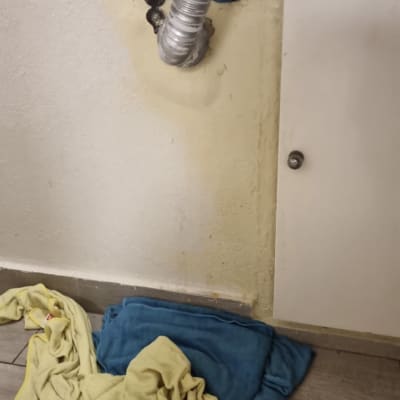 צינור מתכת מתחת לכיור עם מגבות על הרצפה