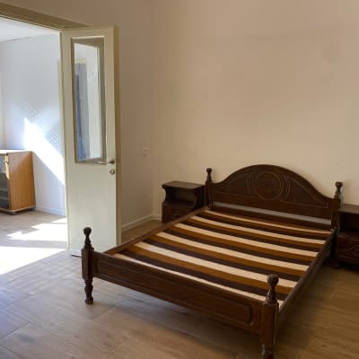 חדר עם מיטה מעץ, שידות לילה ודלת פתוחה