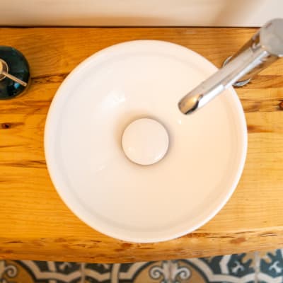 כיור עגול על משטח עץ עם ברז מתכת