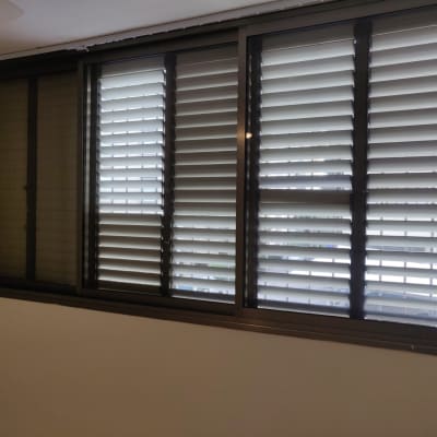 תריסים אפורים על חלון גדול עם מסגרת כהה